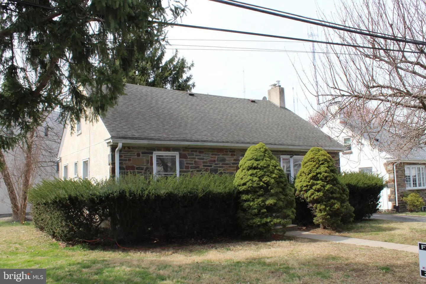 Single-story stone house with trimmed hedges