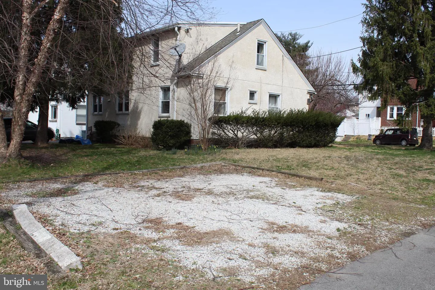 Beige two-story house with gravel parking