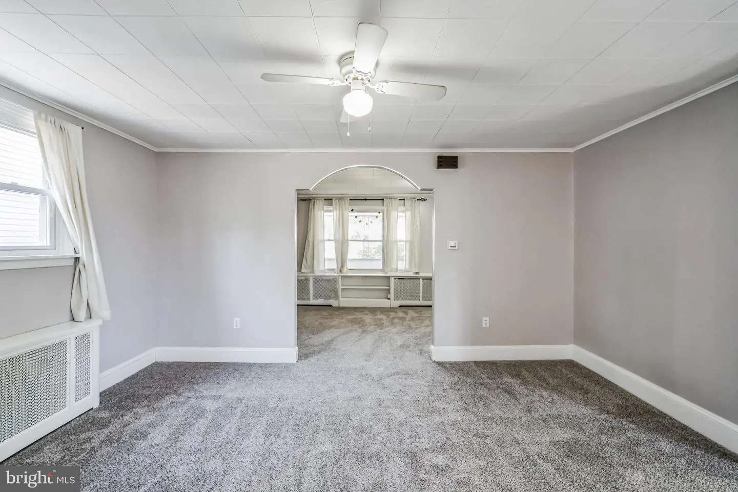 Empty living room with archway to sunroom