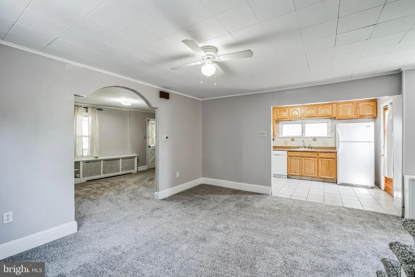 Carpeted living room with archway to kitchen