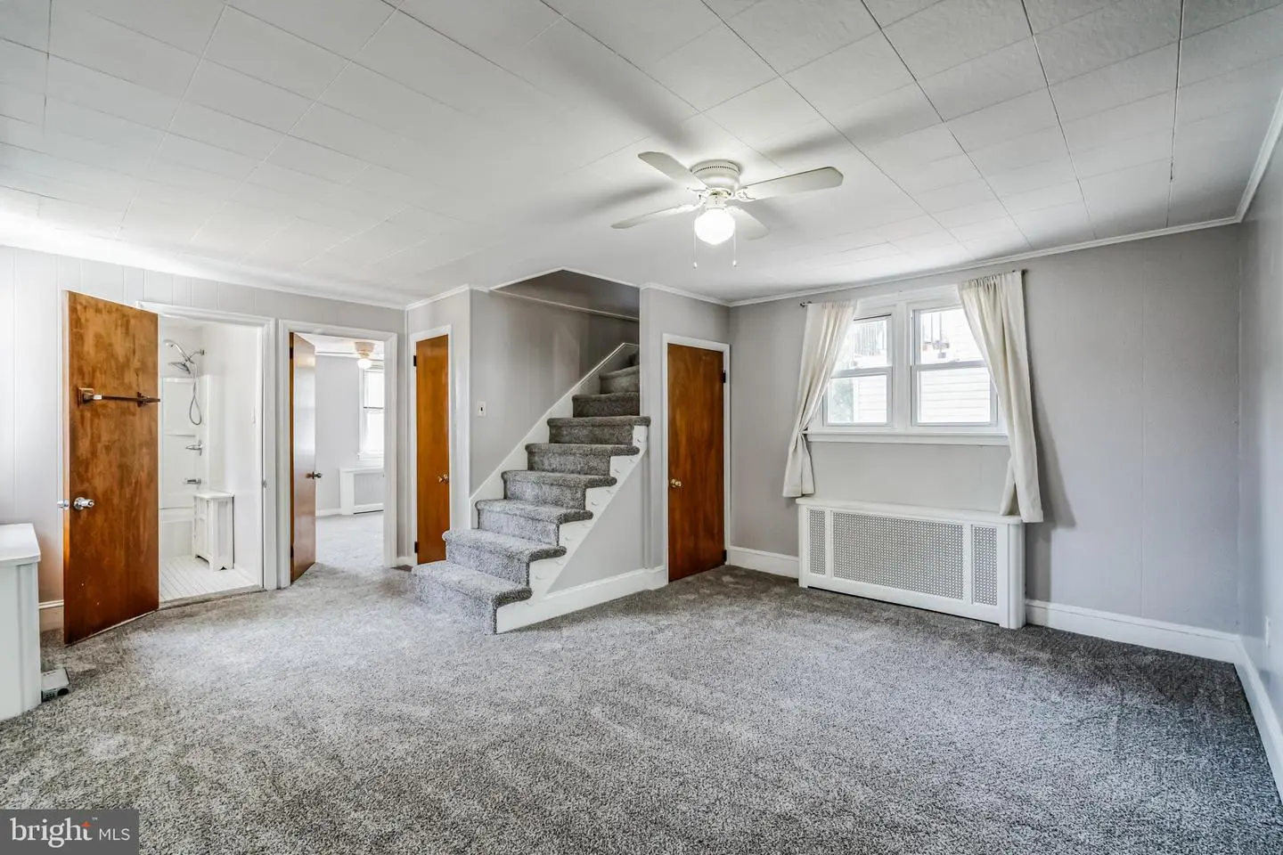 Carpeted living room with staircase and ceiling fan