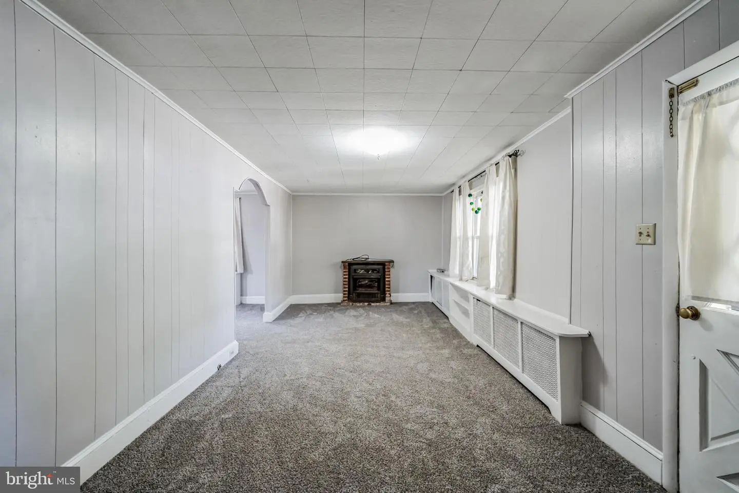 Carpeted gray living room with small fireplace