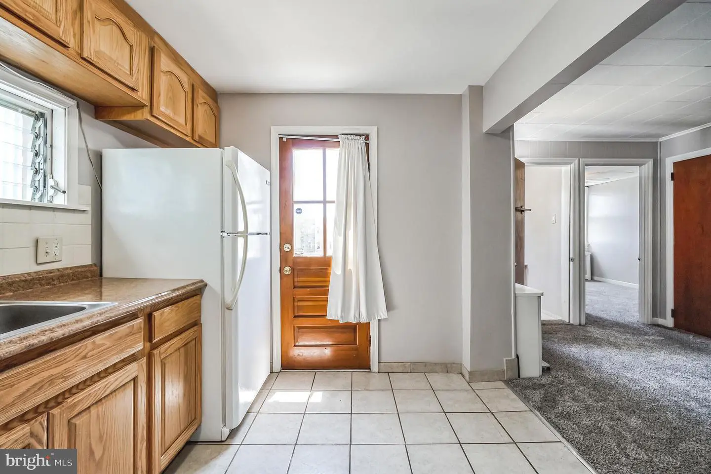Small kitchen with wooden cabinets and white refrigerator