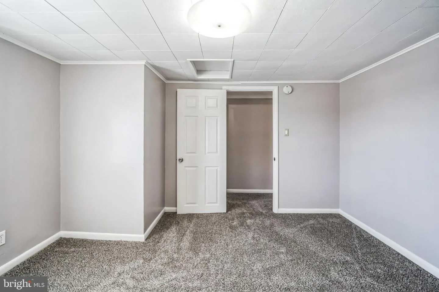 Empty carpeted room with open white door