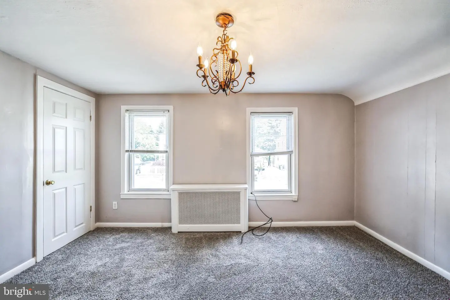 Empty room with chandelier and gray carpet