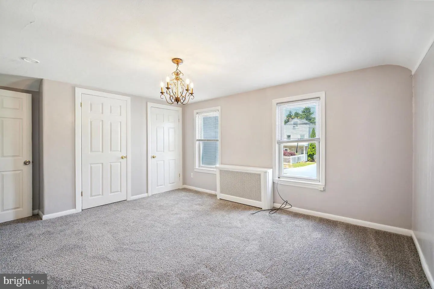Empty carpeted bedroom with chandelier and windows