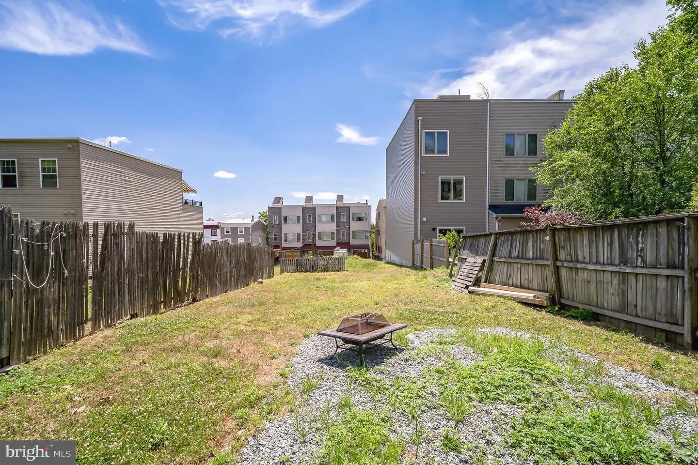 Fenced urban backyard with townhouses and fire pit