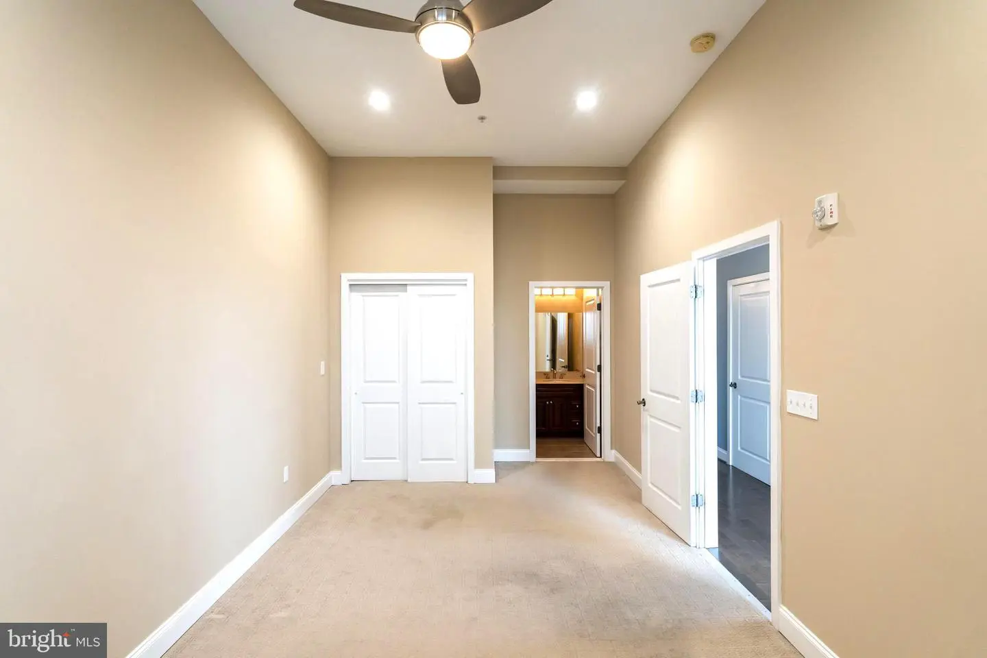 Empty beige bedroom with ceiling fan and closet