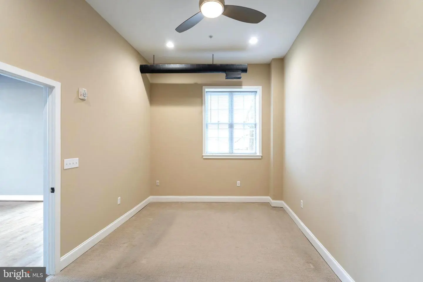 Empty beige room with window and ceiling fan