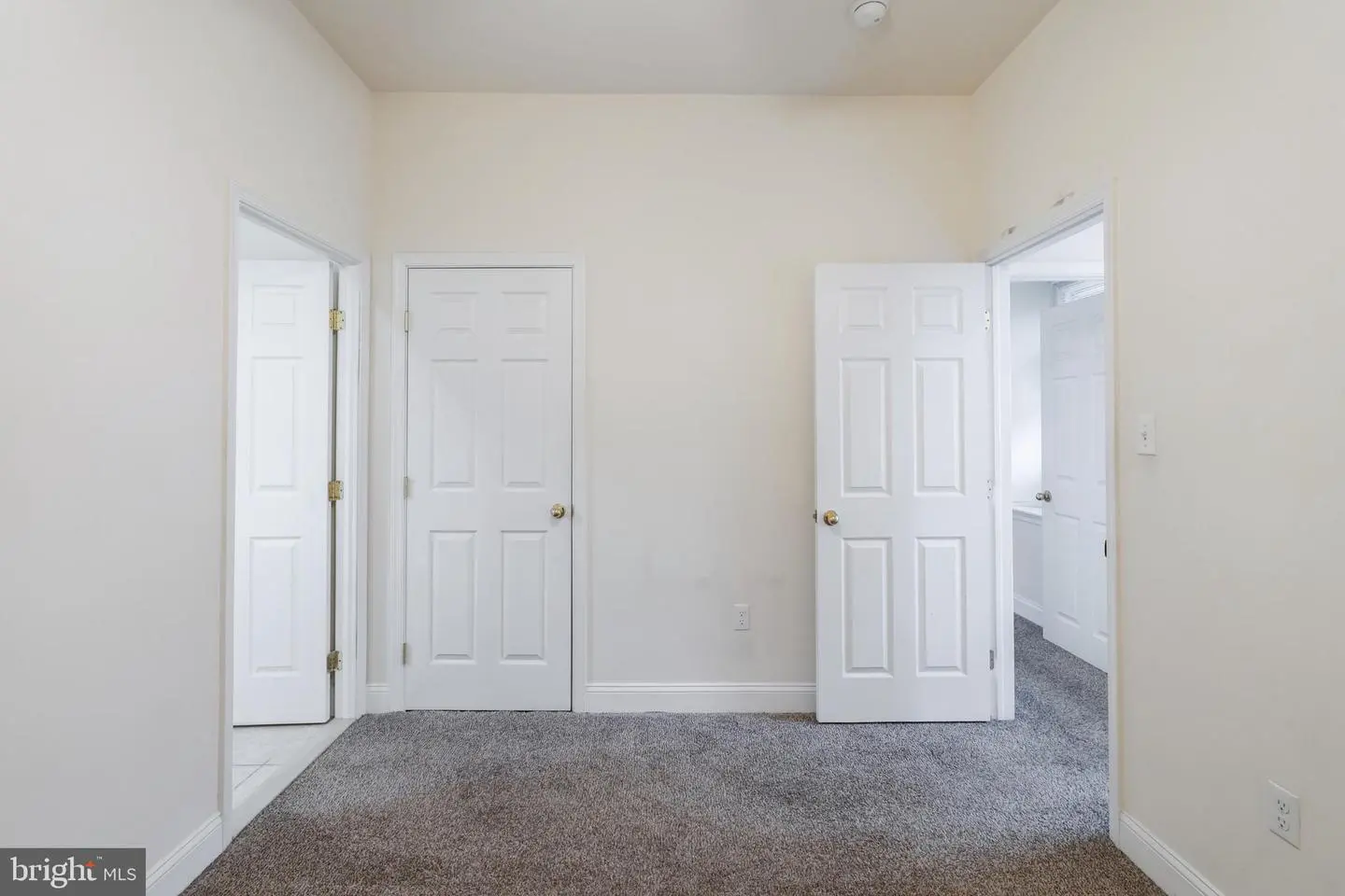 Empty carpeted room with three white doors