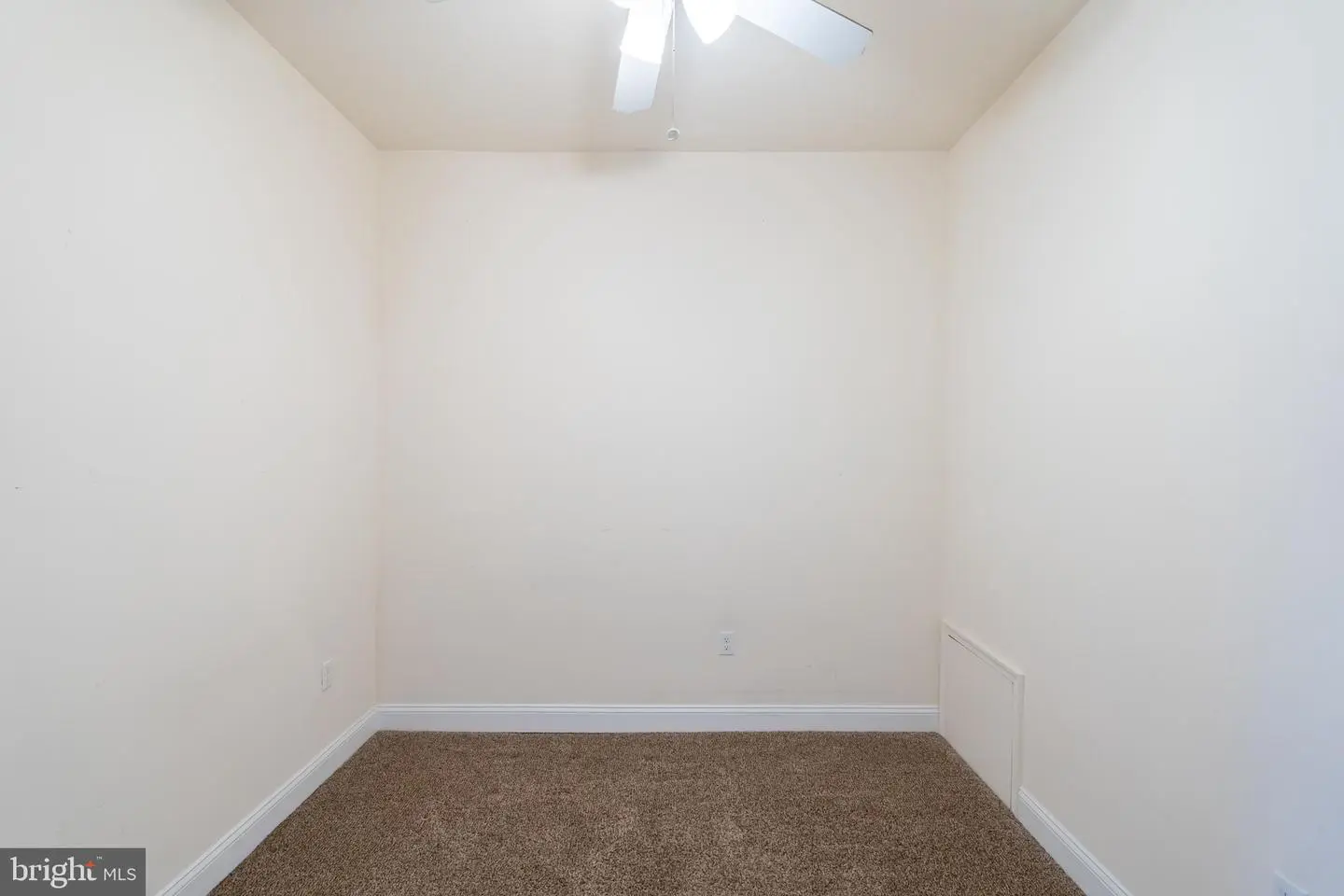 Small empty carpeted room with ceiling fan