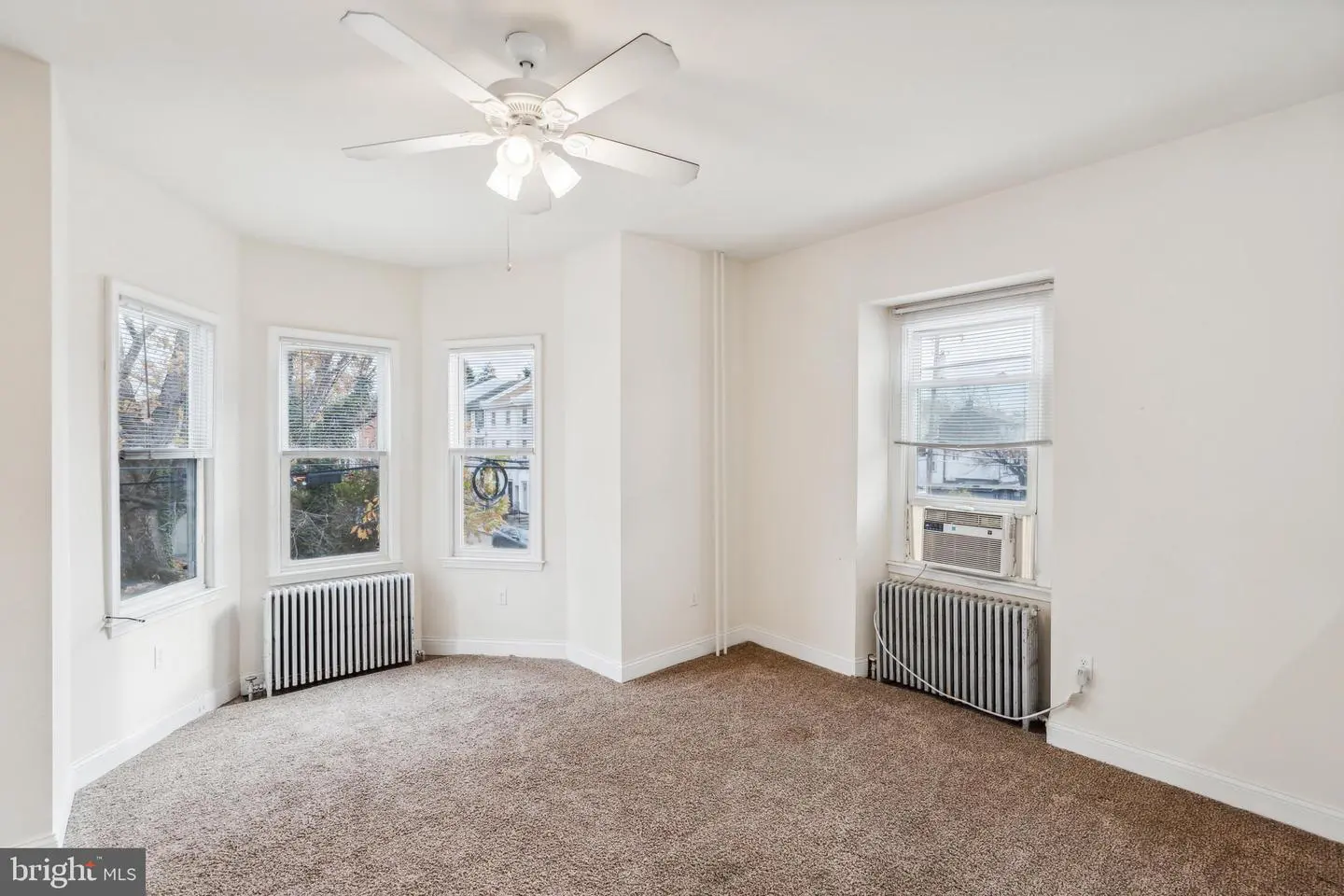 Empty bright bedroom with bay windows, ceiling fan