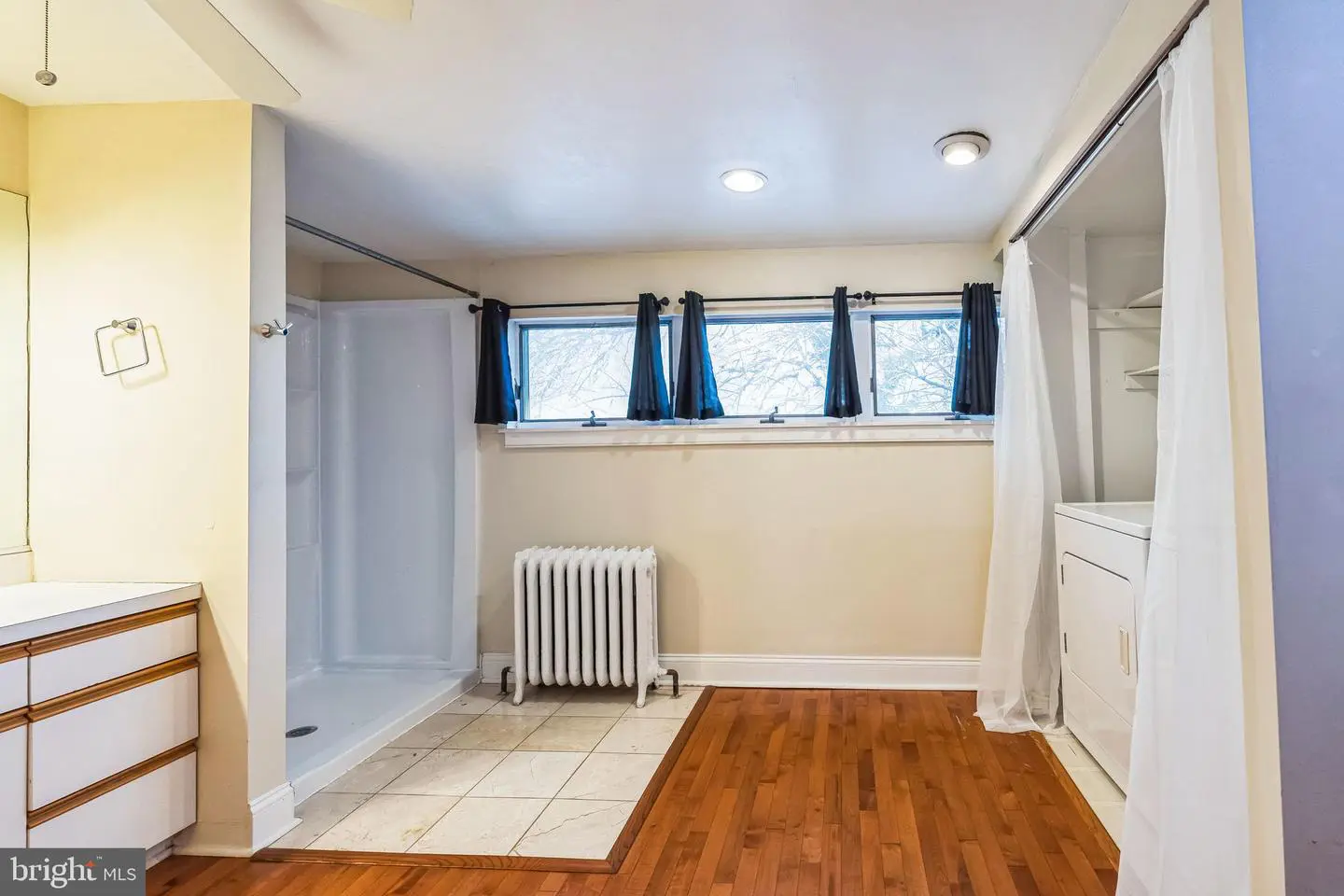 Bathroom with shower, radiator, and hardwood floor