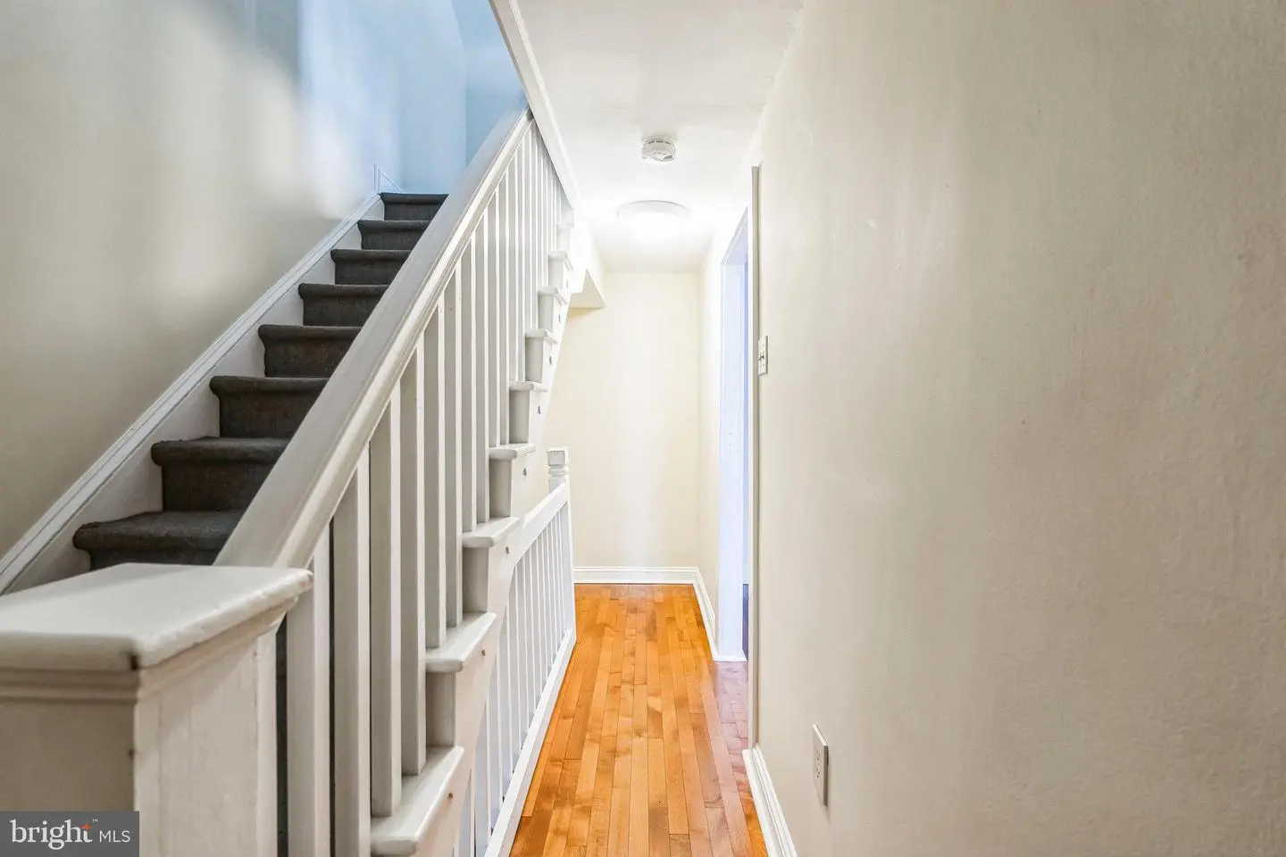 Narrow hallway with staircase and hardwood floor