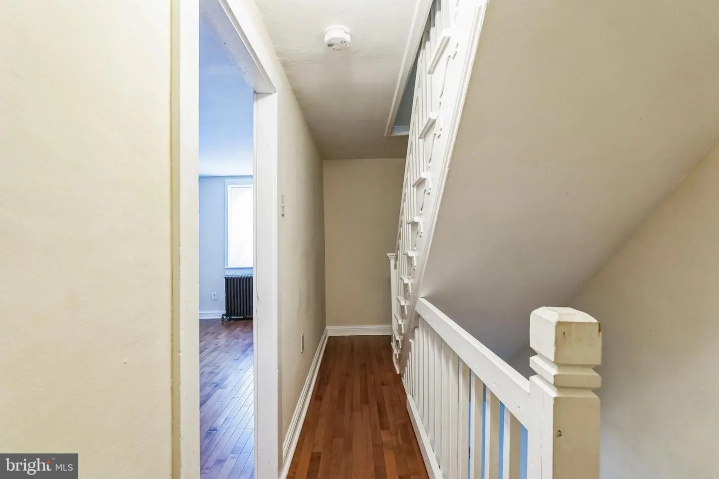 Narrow upstairs hallway with white staircase railing