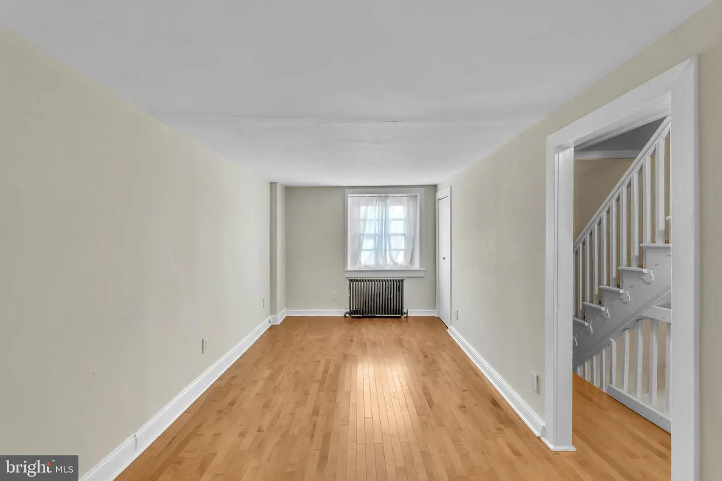 Empty living room with hardwood floors and radiator