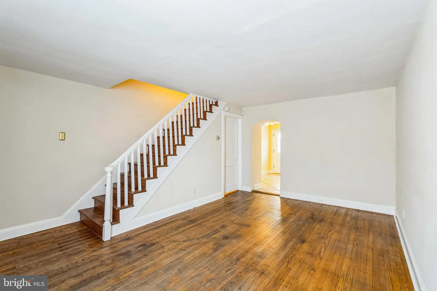 Empty living room with staircase and hardwood floors