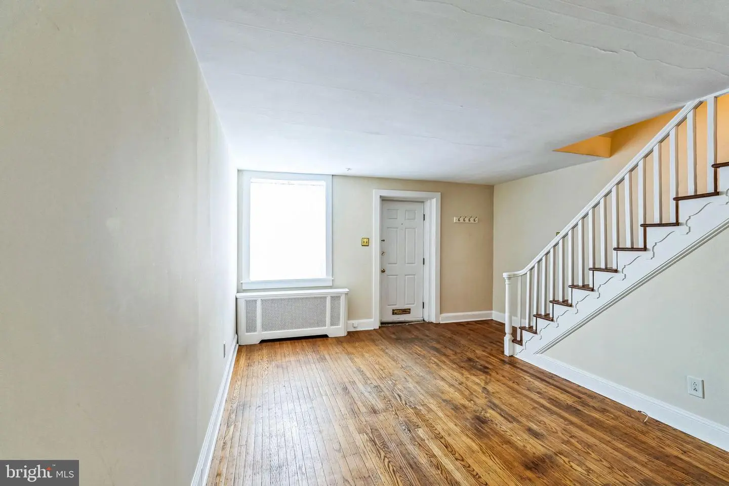 Empty living room with staircase and hardwood floors