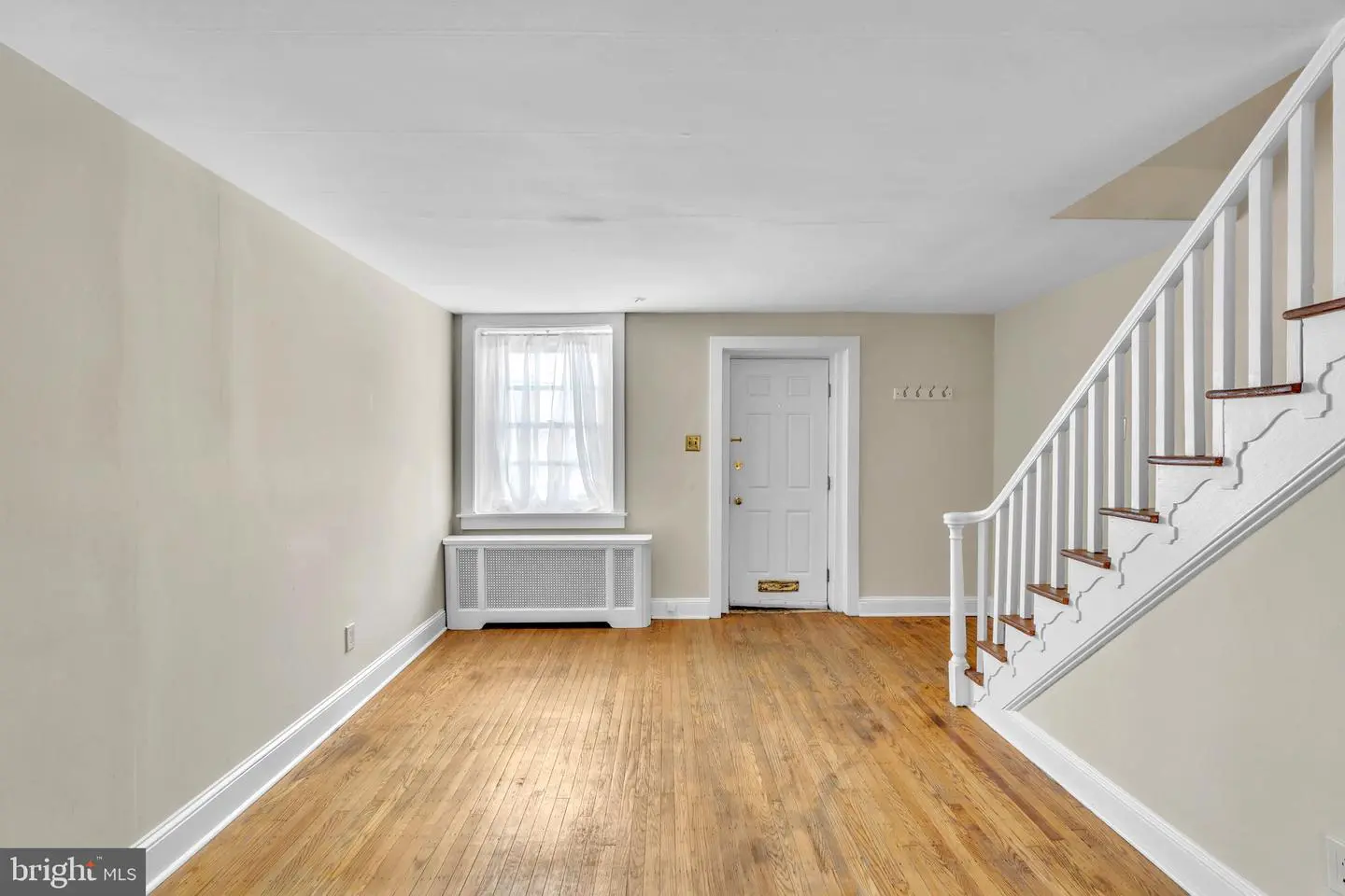 Empty living room with staircase and hardwood floors