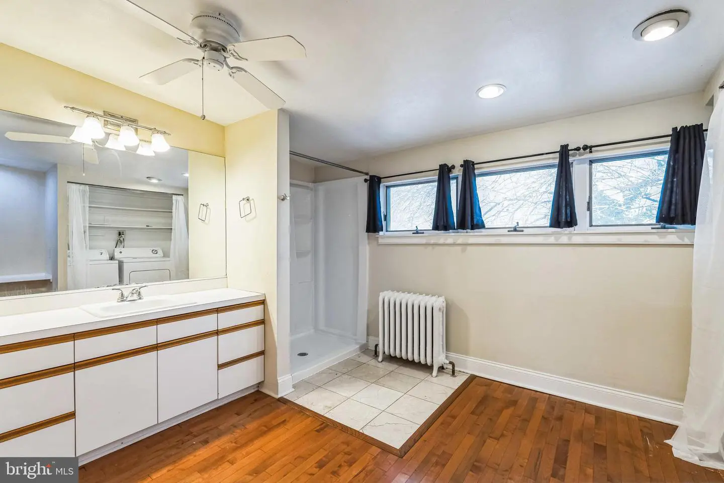 Bathroom with vanity, shower, radiator, hardwood floors