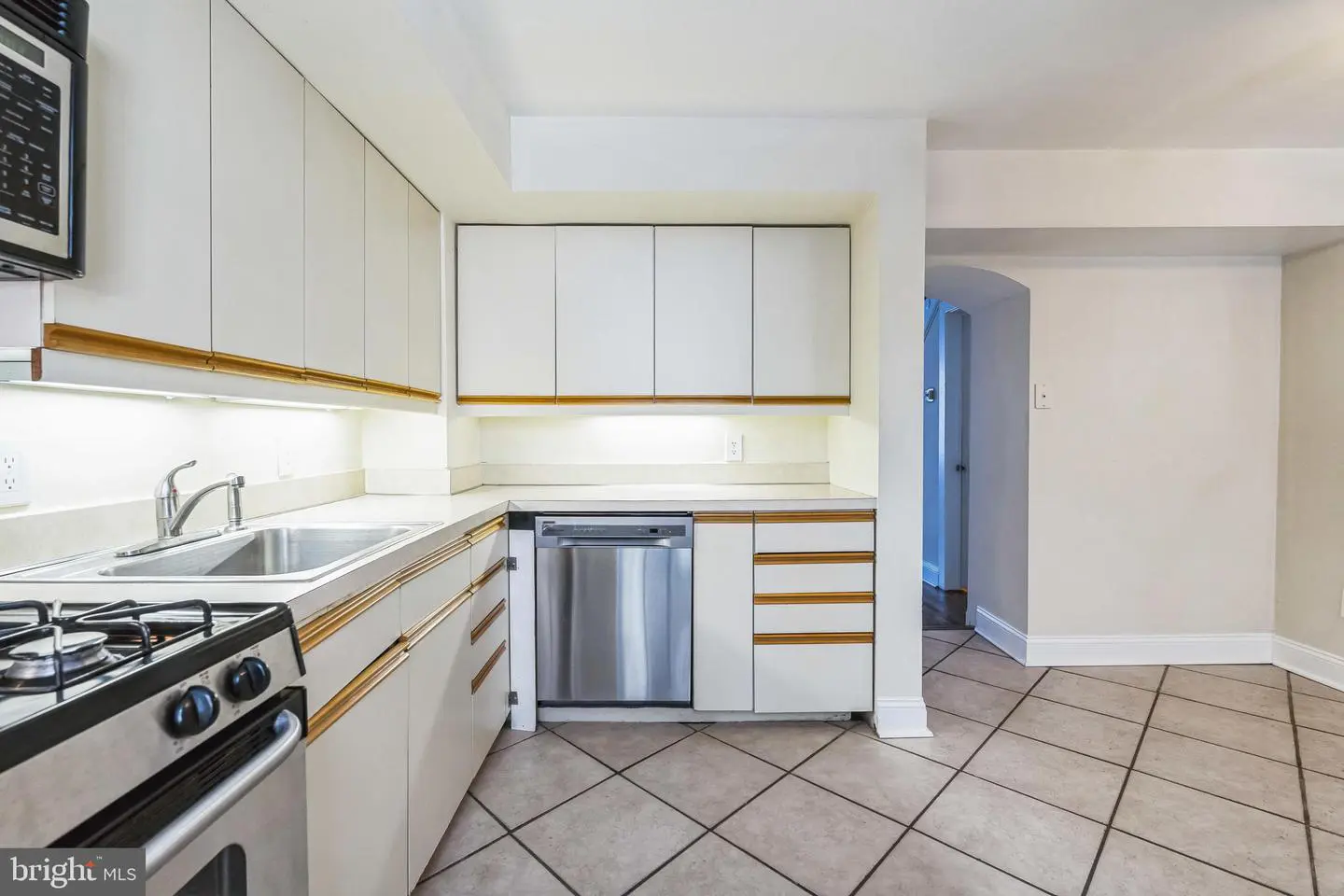 White kitchen with stainless appliances and tiled floor
