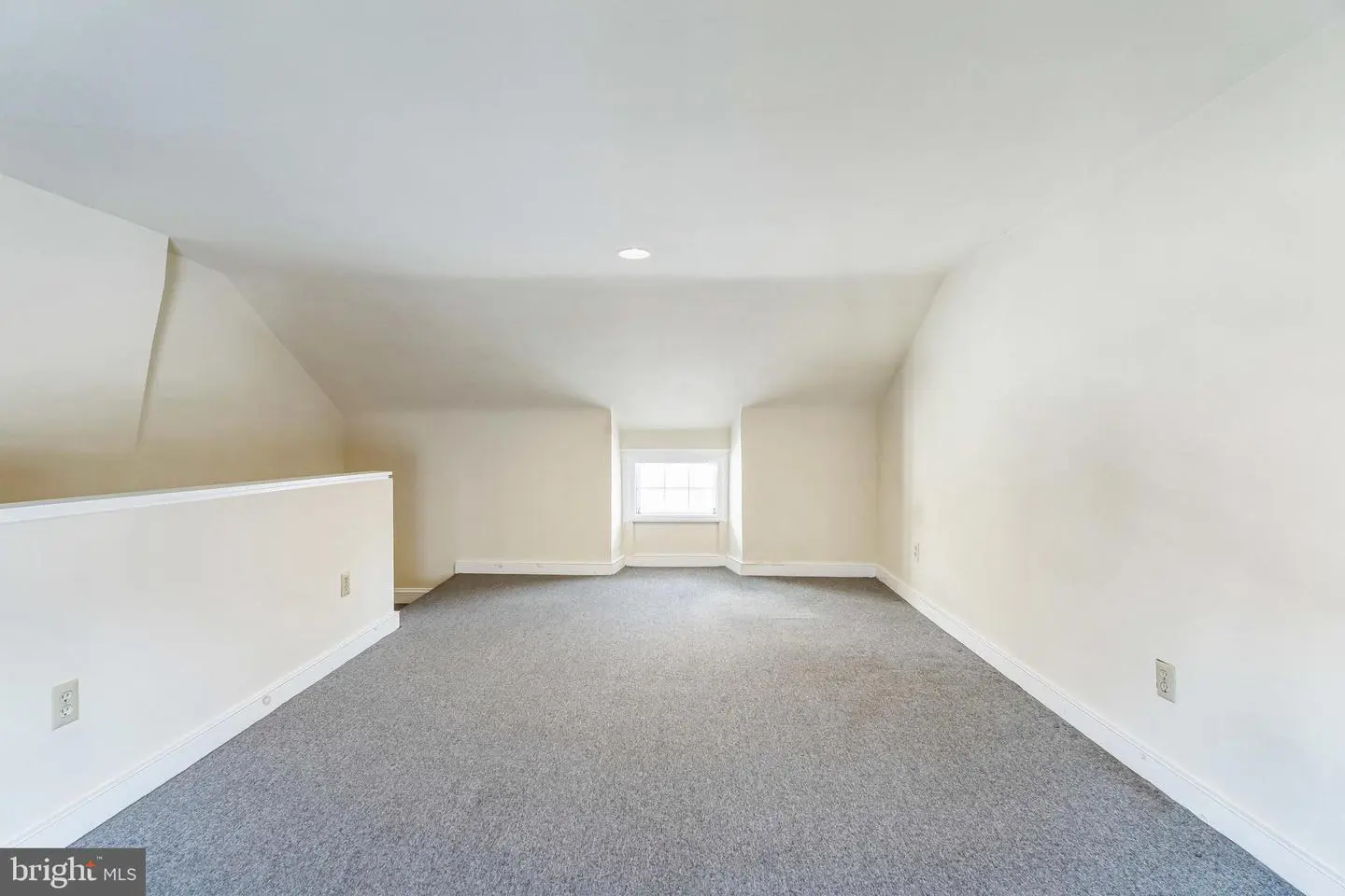 Empty carpeted attic loft with dormer window