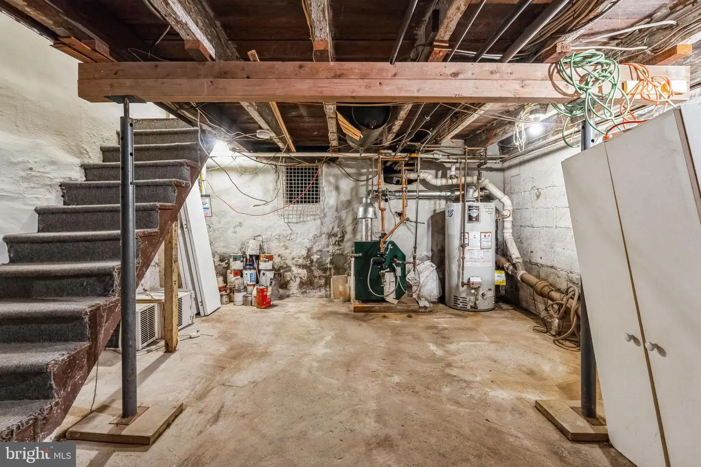 Unfinished basement with exposed beams and furnace