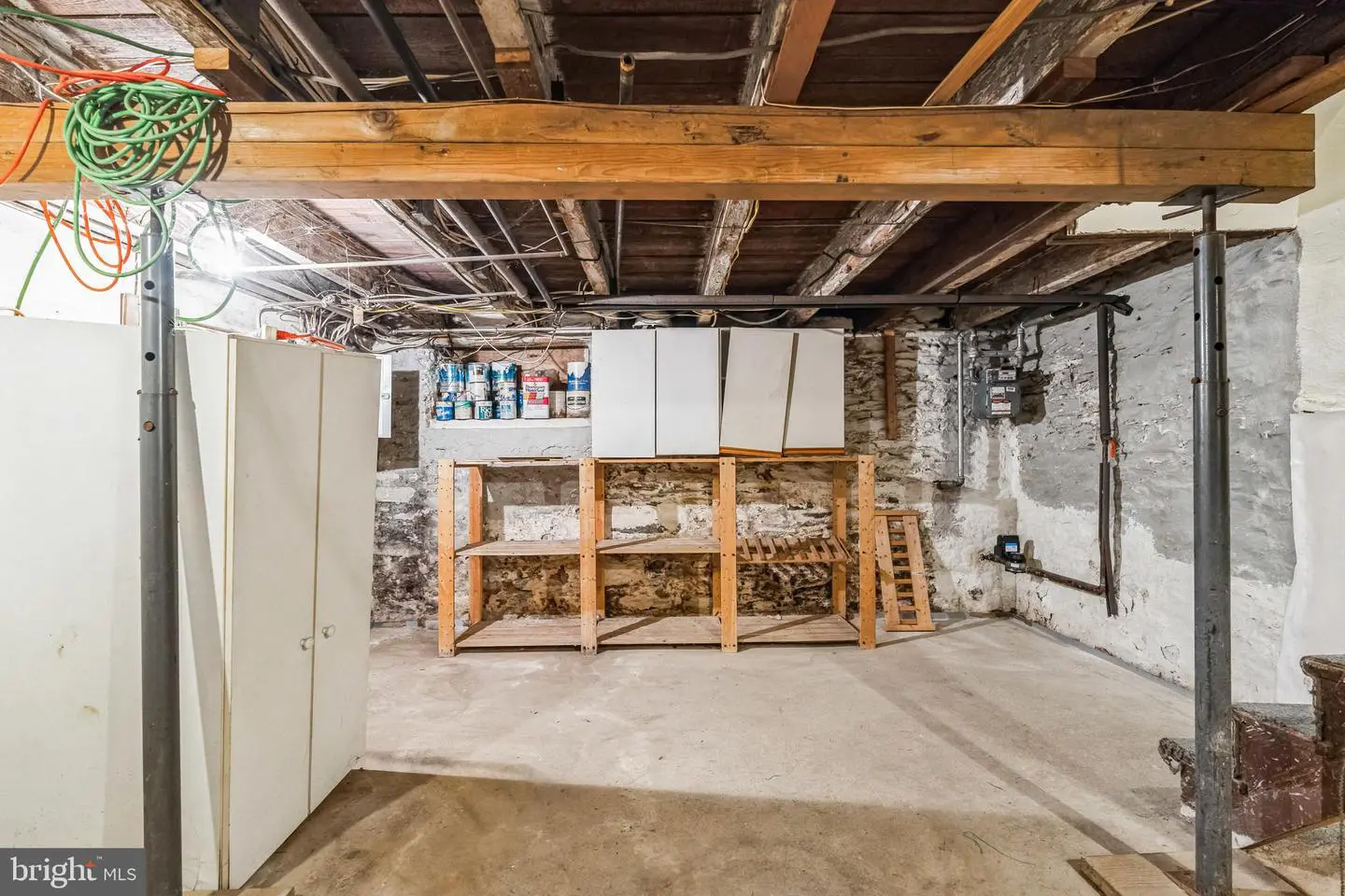 Unfinished basement with shelving and exposed beams