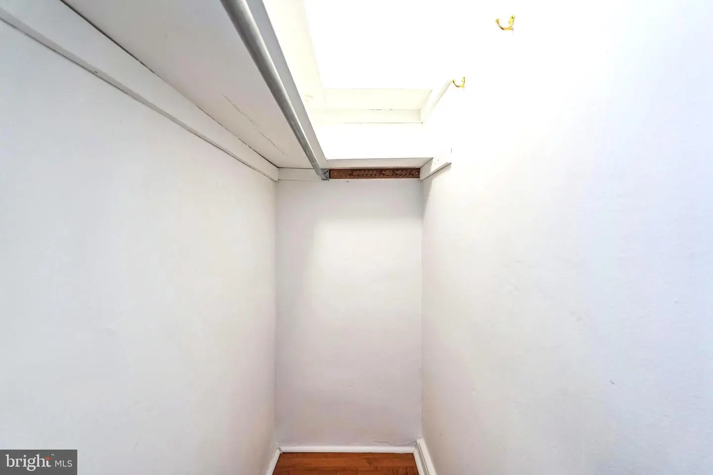 Narrow white storage closet with attic access