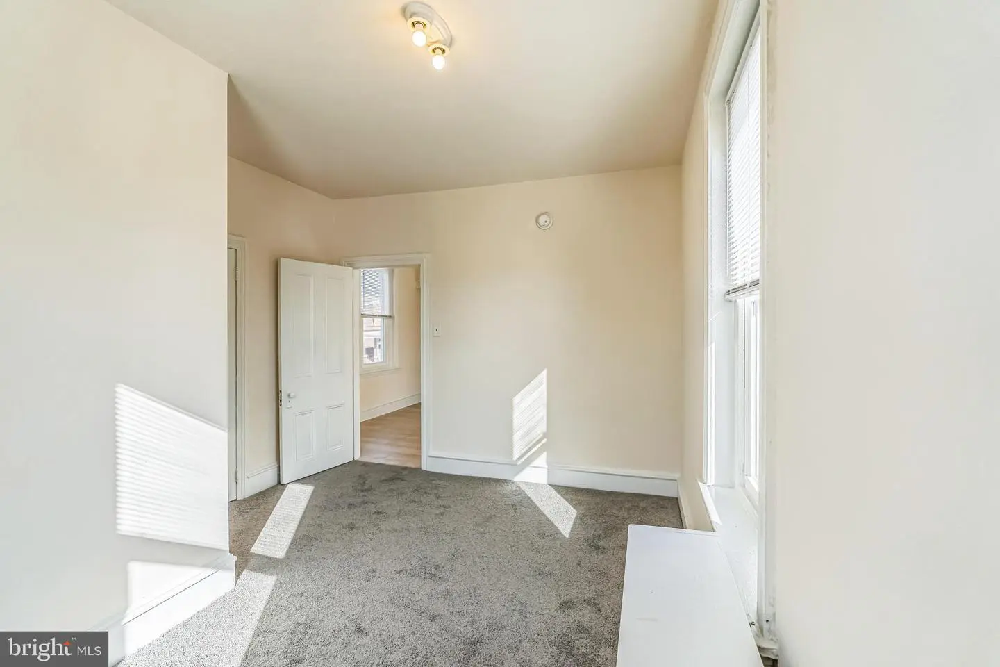 Empty carpeted room with windows and doorway
