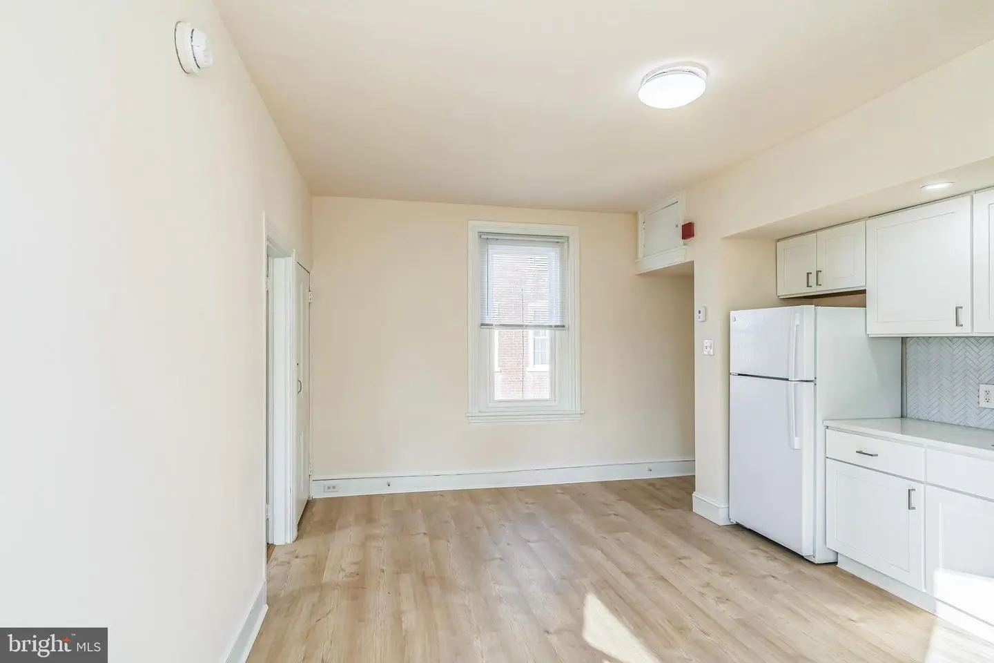 Bright empty studio kitchen with white cabinets
