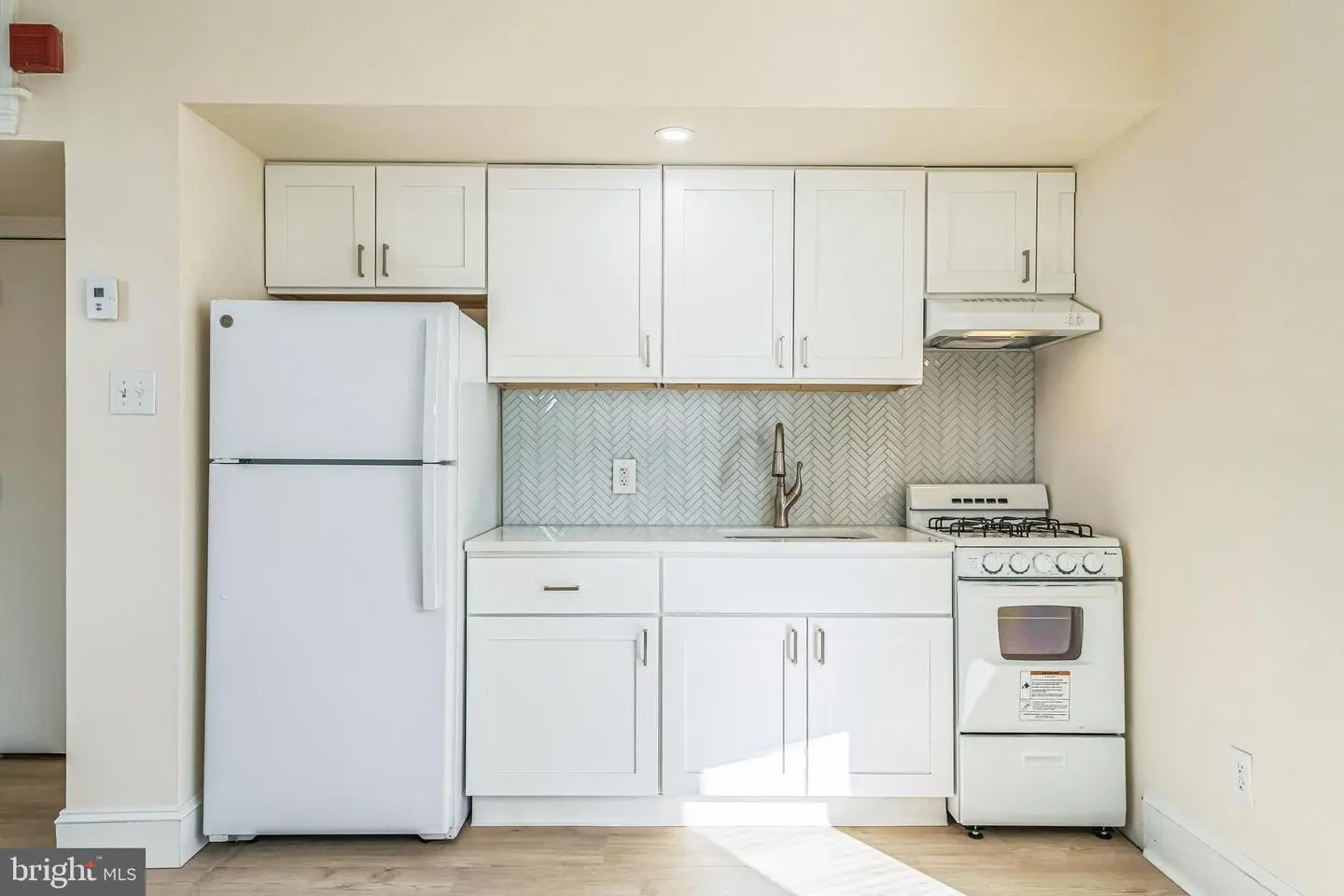 Compact white kitchenette with refrigerator and stove