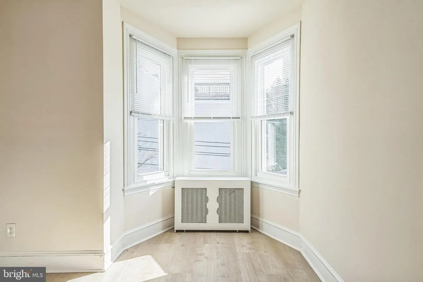 Empty room with bay windows, radiator, hardwood floor