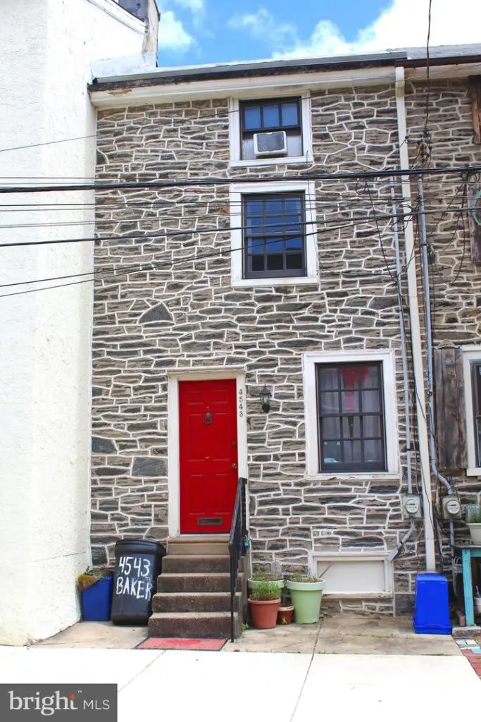 Stone rowhouse with red door and steps