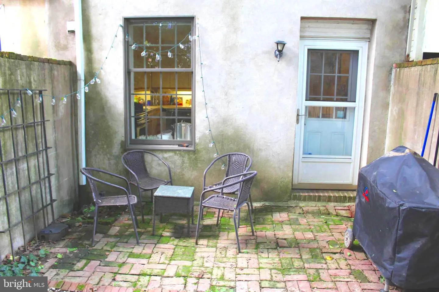 Small brick patio with chairs and grill