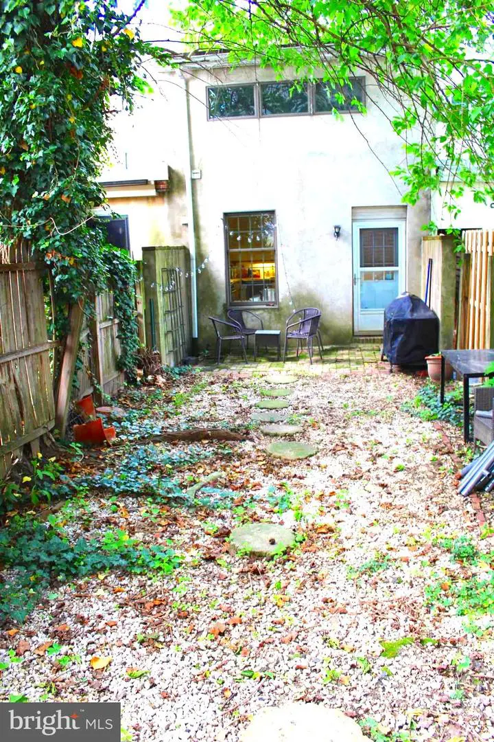 Gravel backyard with chairs, grill, and stepping stones