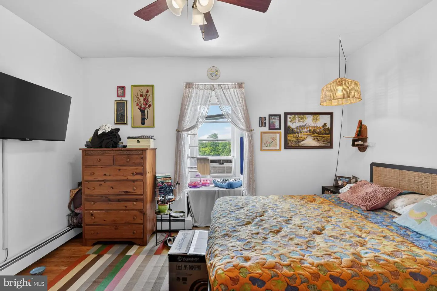 Bedroom with colorful quilt, dresser, window