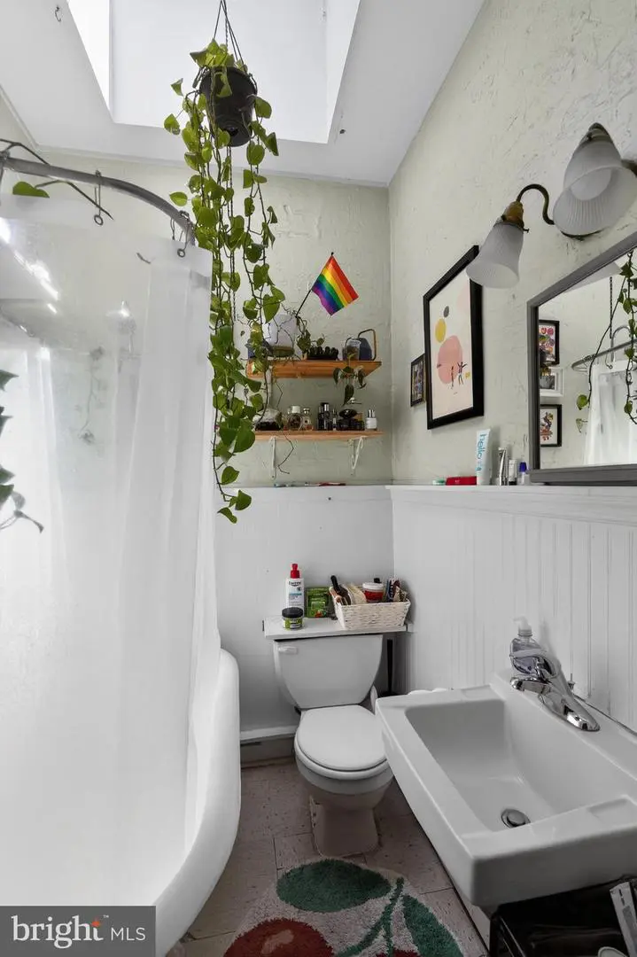 Bright bathroom with hanging plant and rainbow flag