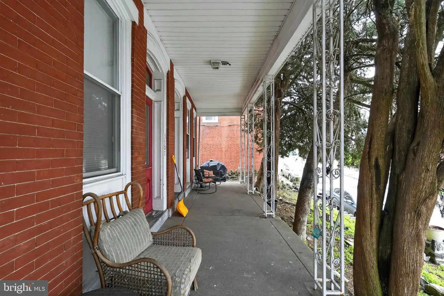 Covered brick porch with wicker chairs