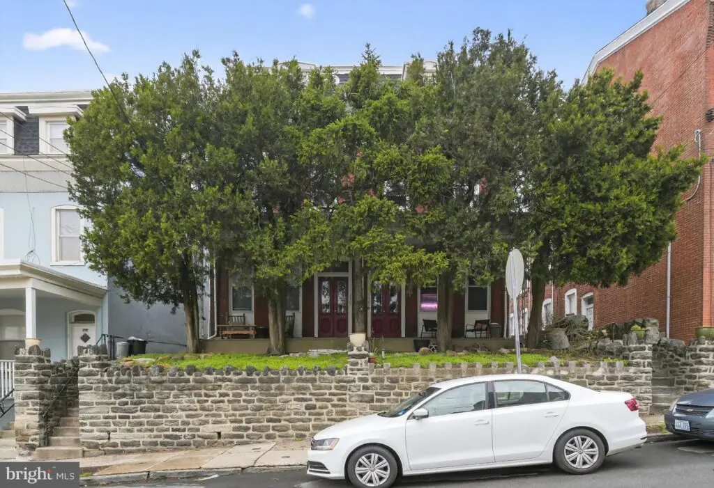 White car parked in front of tree-lined house