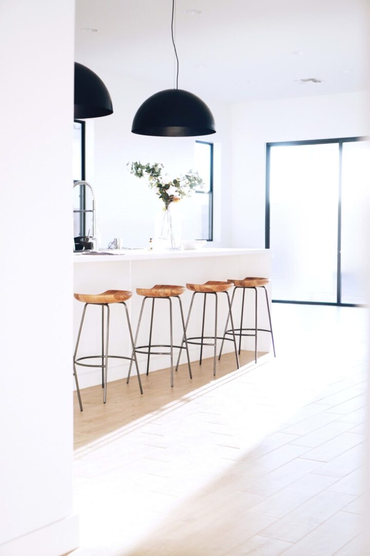 Bright kitchen featuring white surfaces and stools.
